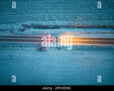 Vista aerea di un'auto che attraversa una foresta al crepuscolo in inverno. Sparato da un drone Foto Stock