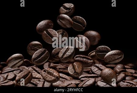 Chicchi di caffè cadenti su fondo nero, profondità di campo completa Foto Stock