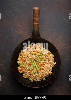 Autentico riso fritto cinese e asiatico con uova e verdure nella vista dall'alto del wok su uno sfondo rustico in cemento. Piatto tradizionale cinese Foto Stock