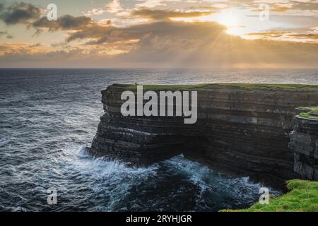 Pescatore in piedi e pesca dal bordo delle alte scogliere di Downpatrick Head, Irlanda Foto Stock