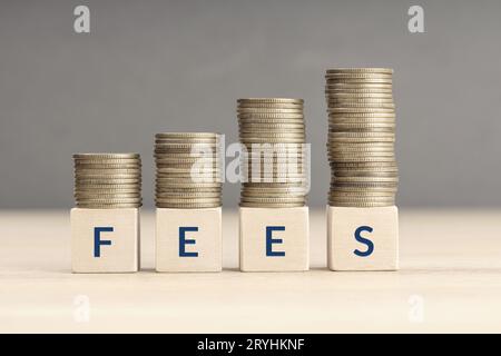 Concetto di aumento delle tasse. Parola di testo su blocchi di legno con monete impilate in pile crescenti. Spazio di copia Foto Stock