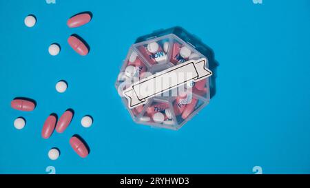 Primo piano della scatola di pillole mediche con dosi di compresse per il giorno assumere la medicina con farmaci rosa bianchi e capsule con nota di carta poliziotto Foto Stock