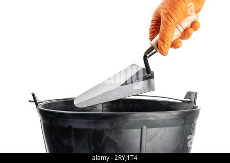 Mano che tiene una cazzuola su un secchio di muratore isolato su sfondo bianco. Spazio di copia Foto Stock