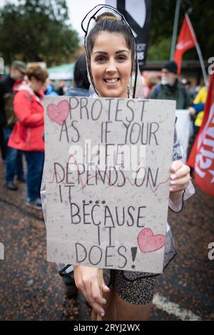 Manchester, Regno Unito. 1 ottobre 2023. Un manifestante tiene un cartello prima dell'inizio della marcia. Migliaia di persone marciano attraverso la città per una manifestazione nazionale durante la Conferenza del Partito Conservatore. Organizzata dall'Assemblea dei popoli e unita ai sindacati, le richieste includono di porre fine al costo della crisi della vita e di difendere l'NHS. Crediti: Andy Barton/Alamy Live News Foto Stock