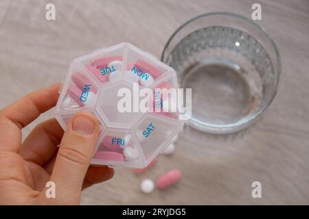 Pillole di smistamento donna Organizer scatti settimanali primo piano della scatola di pillole mediche con dosi di compresse per prendere la medicina quotidiana con bianco Foto Stock