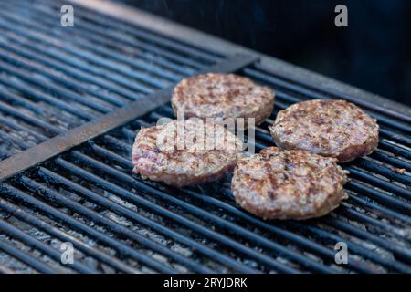 Lo chef prepara carne di hamburger presso il ristorante all'aperto grill. Festival food, fast food, polpette di carne alla griglia con le pinze in mano. Hig Foto Stock