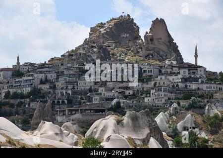 Case sul fianco della montagna e il castello di Uchisar a Uchisar, Cappadocia, Turchia Foto Stock