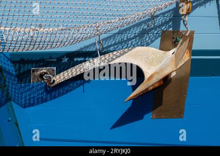 Primo piano di un'ancora su uno scafo blu Foto Stock