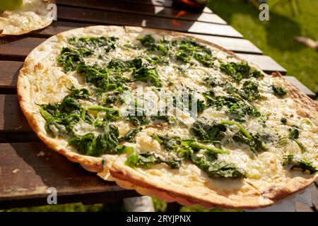 Tarte flambée alsaziana con spinaci e formaggio su un tavolo in un ristorante birreria all'aperto Foto Stock