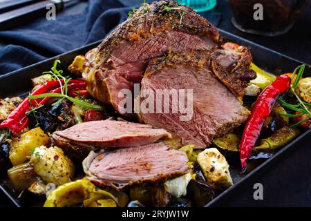 Tradizionale zampa greca di agnello alla griglia con verdure e formaggio feta servita da vicino su un vassoio rustico Foto Stock