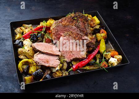 Tradizionale zampa greca di agnello alla griglia con verdure e formaggio feta servita da vicino su un vassoio rustico con spazio copia Foto Stock