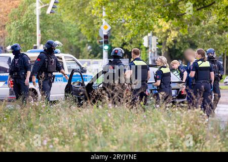 Hannover, Germania. 1 ottobre 2023. Gli agenti di polizia controllano i partecipanti a una processione nuziale e i loro veicoli. I passanti hanno riferito di aver udito degli spari provenienti dalle auto la domenica sera e hanno chiamato il 110. Otto auto sono state perquisite, ma alla fine non è stato trovato nulla. Gli ospiti del matrimonio hanno dovuto lasciare le loro limousine - anche la sposa ha dovuto aspettare su una strada principale a otto corsie nel centro della città con il suo opulento vestito bianco per finire le perquisizioni della polizia Credito: Moritz Frankenberg/dpa - ATTENZIONE: Le persone sono state pixelate per motivi di privacy/dpa/Alamy Live News Foto Stock