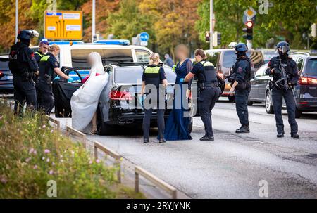 Hannover, Germania. 1 ottobre 2023. Gli agenti di polizia controllano i partecipanti a una processione nuziale e i loro veicoli. I passanti hanno riferito di aver udito degli spari provenienti dalle auto la domenica sera e hanno chiamato il 110. Otto auto sono state perquisite, ma alla fine non è stato trovato nulla. Gli ospiti del matrimonio hanno dovuto lasciare le loro limousine - anche la sposa ha dovuto aspettare su una strada principale a otto corsie nel centro della città con il suo opulento vestito bianco per finire le perquisizioni della polizia Credito: Moritz Frankenberg/dpa - ATTENZIONE: Le persone sono state pixelate per motivi di privacy/dpa/Alamy Live News Foto Stock