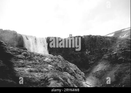 Vista della cascata Gufufoss da lontano, persone in cima, bianche e nere vicino a Seydisfjordur, Islanda Foto Stock