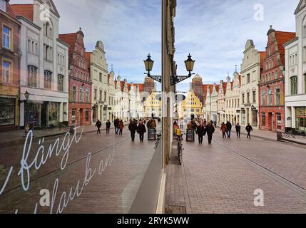 Le facciate a spillo di Kraemerstrasse si riflettono nella vetrina di Galeria, Wismar, Germania Foto Stock