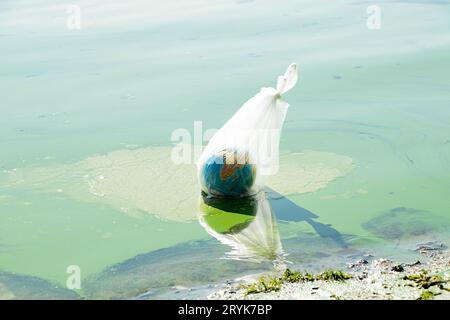 Un globo terrestre in un sacchetto di plastica galleggia in un fiume sporco in Ucraina, inquinamento ambientale, ecologia, riscaldamento globale Foto Stock