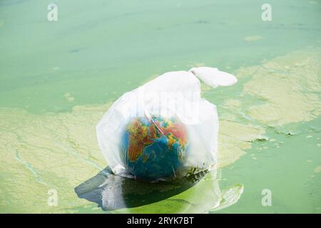 Un globo terrestre in un sacchetto di plastica galleggia in un fiume sporco in Ucraina, inquinamento ambientale, ecologia, riscaldamento globale Foto Stock