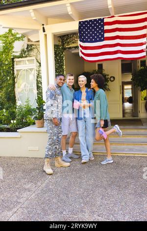 Ritratto di felice gruppo di amici diversi con il soldato americano maschio biraciale abbracciando e sorridendo Foto Stock