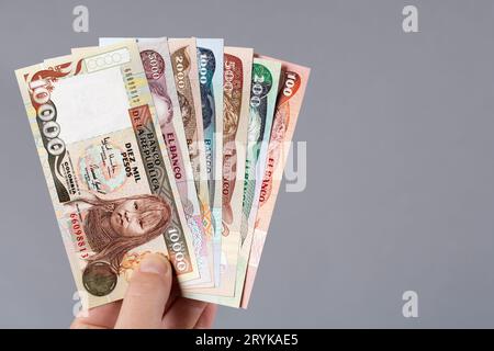 Denaro colombiano - Pesos in mano su sfondo grigio Foto Stock