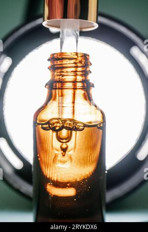 Pipettare con olio cosmetico in un flacone marrone con bolle Foto Stock