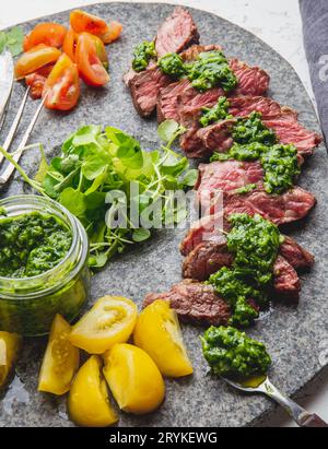 Fette di carne di manzo con salsa di chimmichuri grigio sulla lastra di pietra Foto Stock