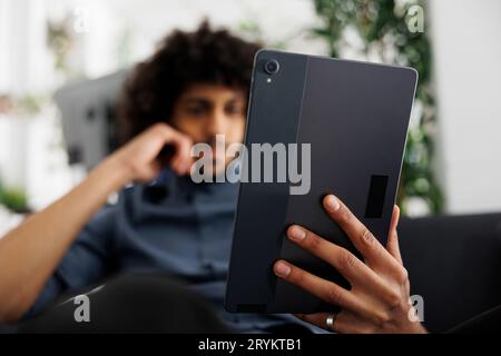 Giovane imprenditore arabo che legge un articolo sul tablet digitale mentre lavora in un ufficio aziendale. Dirigente aziendale di Start-up che controlla la presentazione della strategia di marketing del progetto Foto Stock