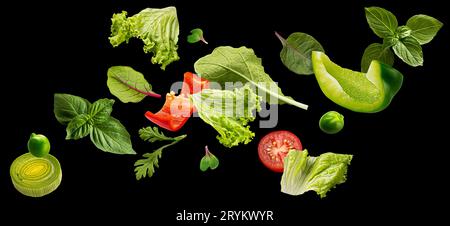 Foglie di insalata cadenti isolate su sfondo nero Foto Stock