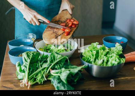 Una donna dalle mani irriconoscibili prepara un'insalata e mette gli ingredienti in un recipiente grande. Come preparare una vespa magra del Mediterraneo Foto Stock