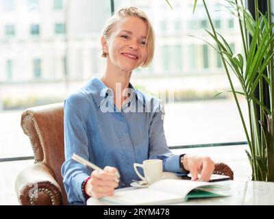 Elegante donna dirigente che scrive in un notebook in un bar. Donna d'affari Foto Stock