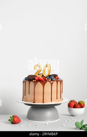 Torta di compleanno al cioccolato con frutti di bosco, biscotti e ventine candele dorate su sfondo bianco, spazio copia Foto Stock