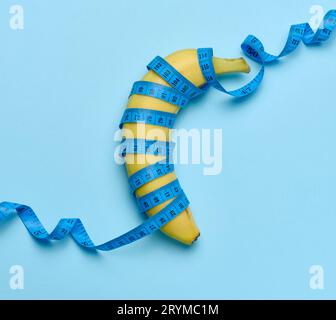 Banana matura gialla avvolta in un nastro di misurazione, concetto di perdita di peso, vista dall'alto Foto Stock