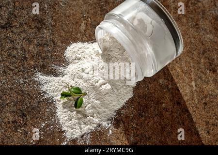 Un vasetto aperto di scrub in polvere di enzima facciale con un ciuffo verde. Foto Stock