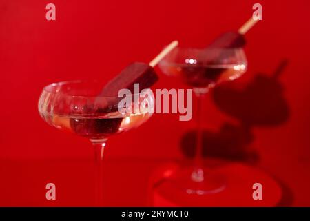 Due bicchieri di champagne e gelato al cioccolato sul podio. Elegante cocktail alcolico su sfondo rosso. Foto Stock