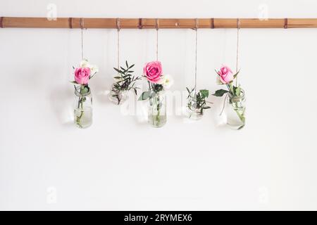 Elegante decorazione natalizia fai da te. I fiori nei vasi sono sospesi dalla parete bianca in camera. Decorazioni romantiche stagionali sul davanti Foto Stock