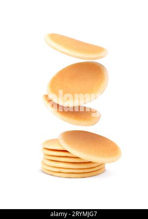 Molti gustosi pancake freschi che cadono su sfondo bianco Foto Stock