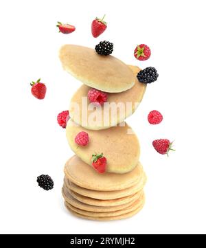 Molti pancake freschi e frutti di bosco che cadono sulla pila su sfondo bianco Foto Stock