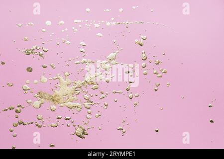 Gocce di potale e spruzzi d'oro su cartone rosa. Background creativo Foto Stock