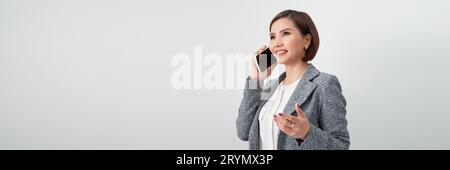 Giovane donna elegante che parla al telefono cellulare su sfondo banner bianco Foto Stock