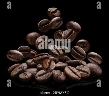 I chicchi di caffè cadenti sono isolati su sfondo nero Foto Stock