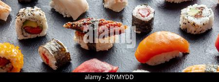 Panorama dell'assortimento di sushi. Rotoli, maki, nigiri su sfondo nero Foto Stock