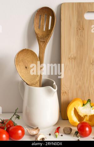 Utensili da cucina in legno, verdure e spezie sullo sfondo del tavolo Foto Stock