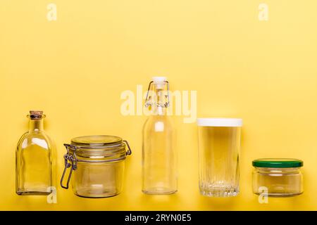 Set di vasetti e flaconi di vetro su sfondo giallo. Concetto di plastica zero Foto Stock