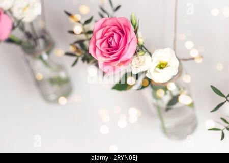 Arredamento per le vacanze bellissimo ed elegante. Le rose in vasi sono sospese dalla parete bianca. Decorazione romantica stagionale, selettiva Foto Stock