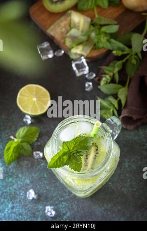 Bevanda rinfrescante estiva con kiwi, cetriolo, lime e ghiaccio, mojito o soda con cetriolo su un tavolo di pietra scura. Vista dall'alto piatto Foto Stock