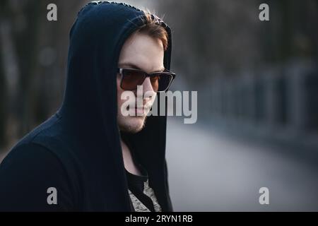 Ritratto in primo piano di un uomo misterioso con cappuccio nero e occhiali da sole Foto Stock