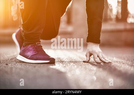Immagine ritagliata di mani che legano i lacci delle scarpe su sneaker, sfondo della superficie running. sportivo che si allena prima di un allenamento sportivo Foto Stock