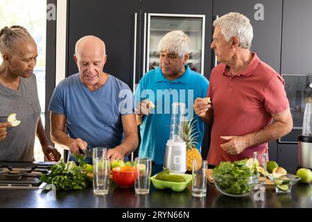 Felice diversi amici anziani discutere gli ingredienti per la preparazione di frullati sani in cucina Foto Stock