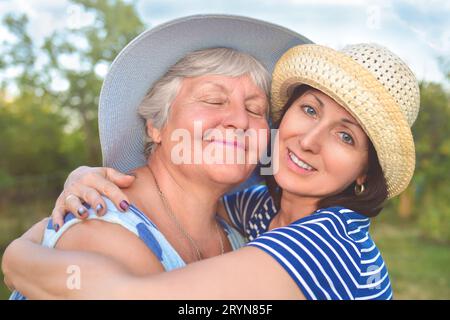 Felice figlia abbracciando la sua madre sorridente. Foto Stock