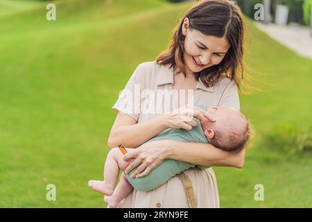 La madre amorevole applica delicatamente oli aromatici lenitivi al suo prezioso neonato, creando un'atmosfera rilassante e nutriente Foto Stock