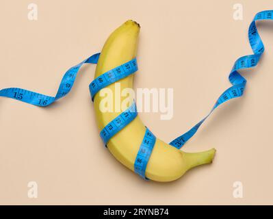 Banana matura gialla avvolta in un nastro di misurazione, concetto di perdita di peso, vista dall'alto Foto Stock